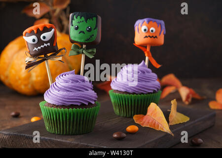 Festliche Halloween cupcakes dekoriert mit Marshmallow in Schokolade oder Kuchen und Süßigkeiten. Lustige monster Gesicht behandelt. Stockfoto