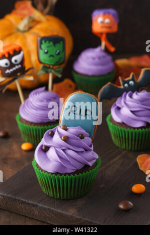 Satz von Halloween Cupcakes mit Lebkuchen Kekse und Kuchen Pops oder in Schokolade getauchte Marshmallow Monster mit lustigen Gesichtern dekoriert. Aus dunklem Holz hinterg Stockfoto