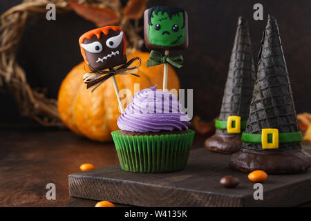 Halloween Kuchen dekoriert mit Kuchen oder Schokolade getauchte Marshmallow Monster mit lustigen Gesichtern und Wafer Hexe Hüte. Selektive konzentrieren. Stockfoto
