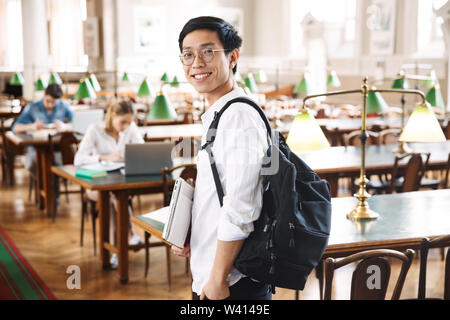 Lächelnd asiatischen Teenager Schüler studieren an der Bibliothek, holding Laptop Stockfoto