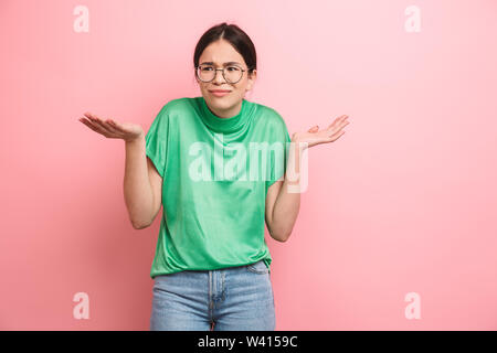 Foto der bescheidene junge Mädchen tragen runde Brillen bis werfen ihre Hände isoliert über rosa Hintergrund Stockfoto