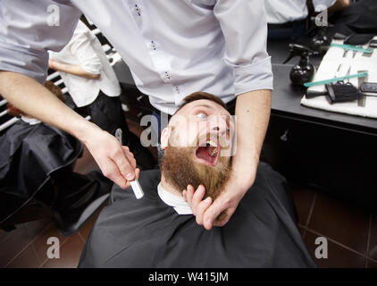 Bärtiger Mann mit Angst sitzt in einem Friseursalon. Stockfoto