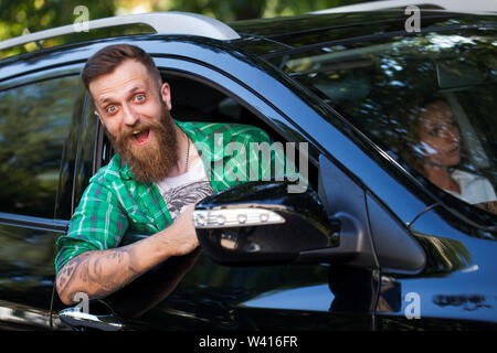Fröhliche bärtiger Mann im Auto auf der Straße. Stockfoto