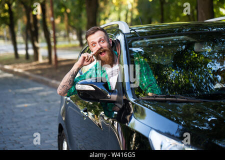 Fröhliche bärtiger Mann im Auto auf der Straße. Stockfoto