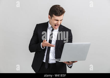 Portrait von betonte gereizte junge Unternehmer in Bürosoftware zu schreien, während sie Laptop auf weißem Hintergrund Stockfoto