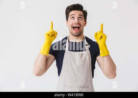 Foto der kaukasischen jungen Mann tragen gelbe Gummihandschuhe Hände schutz Pointing Finger an Copyspace während der Reinigung Haus über Weiß isoliert Stockfoto
