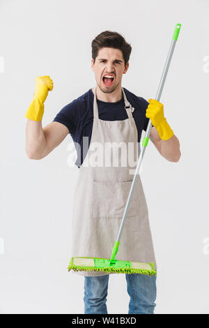 Foto von gutaussehenden jungen Mann tragen gelbe Gummihandschuhe Hände Schutz holding Mop während der Reinigung Haus auf weißem Hintergrund Stockfoto