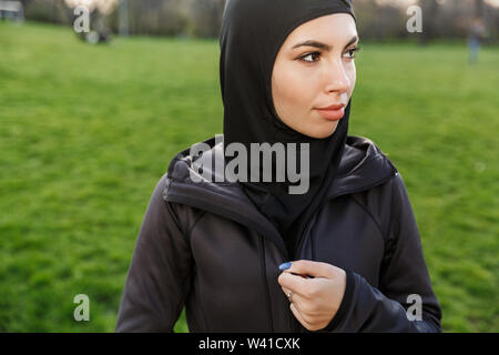 Portrait von attraktiven athletische muslimische Frau in religiösen Schwarz hijab im Green Park gekleidet beim Training im Freien Stockfoto