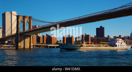 Frachtschiff vorbei unter der Brooklyn Bridge Stockfoto