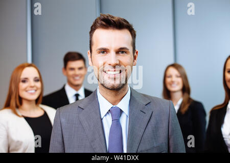 Portrait von Happy Team Leader mit einer Gruppe von Geschäftsleuten im Hintergrund Stockfoto