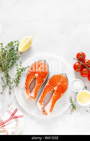 Frischer Lachs Steaks mit Zutaten zum Kochen auf dem Whiteboard, Ansicht von oben Stockfoto