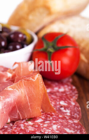 Eine Platte mit Wurst, Oliven, Tomaten und Brötchen. Im Tapas Stil Sortiment. Vorsätzliche flache Tiefenschärfe. Stockfoto