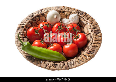 Frische Tomaten, Paprika, Zwiebel und Knoblauch in einem Weidenkorb mit weißem Hintergrund Stockfoto