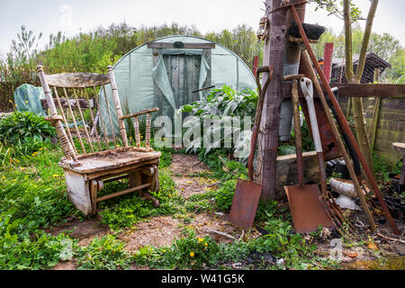 Garten mit Gewächshaus, alt und rostet Garten Werkzeuge und Ausrüstung und einem alten hölzernen Schaukelstuhl, Kilwinning, Ayrshire, Schottland, Großbritannien verlassen Stockfoto