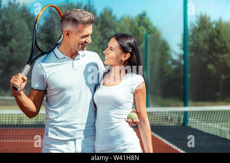 Strahlende dunkelhaarige Frau an ihrem stattlichen Mann sucht Stockfoto