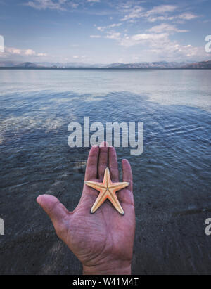 Hand mit einem Seestern durch den Ozean. Corfu Griechenland Stockfoto
