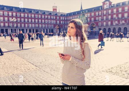 Verlorene junge touristische Frau Kontrolle smart Handy versuchen, Richtungen zu finden. Suchen besorgt und durchdachte Beratung das Handy app. In Touris Stockfoto
