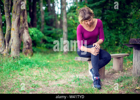 Gesundheit, Medizin, Personen Konzept. Frau leiden unter Schmerzen im Knie outdoor Stockfoto