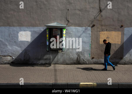 SAINT-Petersburg, Russland - 13. Juni, 2014: erwachsener Mann mit Kopfhörern zu Fuß auf der Seite in der Nähe der bemalten Wand mit Call-Box. Stockfoto