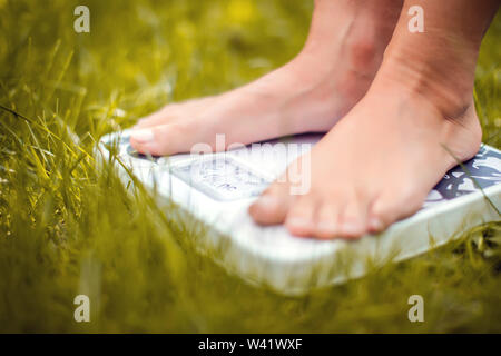 Gewicht Konzept verlieren. Eine Person auf einer Skala auf einem Gras messen kg Outdoor Stockfoto