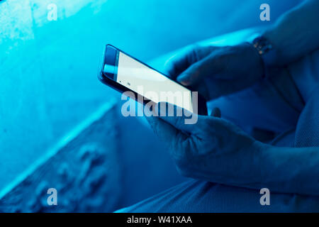 Blick auf Nahaufnahme des Menschen Hände smartphone Holding in Blue Space Stockfoto