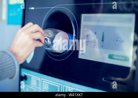 Käufer zurück, um ihre Flaschen und Dosen von wiederverwendbaren Verpackungen in einem umgekehrten Automaten. Stockfoto