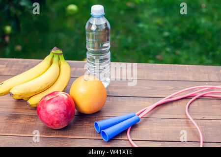 Gesundes Essen. Frisches Obst, Wasser und Seil springen auf den Tisch. Stockfoto
