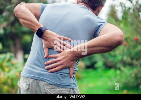 Menschen, Gesundheitswesen und Problem-Konzept - ein Mann leidet unter Schmerzen im Rücken oder Zügel outdoor Stockfoto