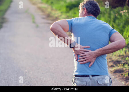 Menschen, Gesundheitswesen und Problem-Konzept - ein Mann leidet unter Schmerzen im Rücken oder Zügel outdoor Stockfoto