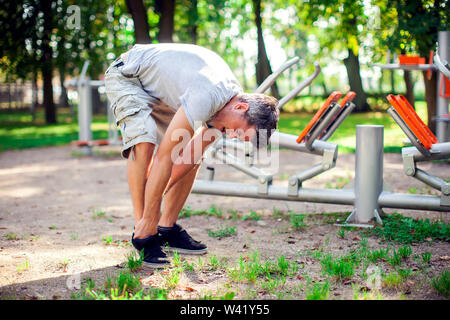 Ein unglücklicher Mann Gefühl Schmerz in seinem Fuß beim Sport und Training im Park. Sport-, Medizin- und Personen Konzept Stockfoto