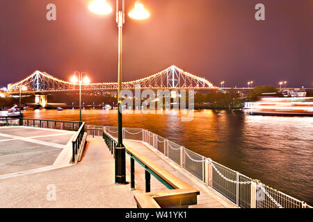 Stein Straße und streetlight blinken am Fluss in die Stadt bei Nacht mit langen Brücke, die mit Lichtern von Brisbane, Queensland beleuchtet, Stockfoto