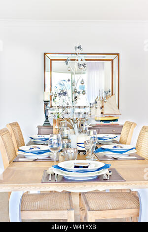 Spielzeug Schiff weiter in der Nähe der Wand Spiegel zu Kerze, keramische Platten mit Brille am Esstisch, Löffel mit Messer in der Nähe der Schale, sehr glänzend und sauber, ni Stockfoto