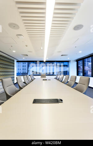 Moderne Büro sieht entlang der weißen langen Tisch mit weißen Stühlen Glasfenstern umgeben Stockfoto