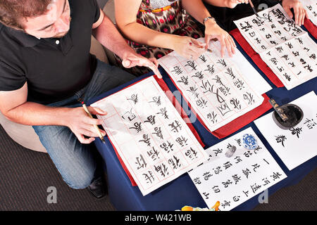Blick von oben auf die Studenten schreiben wie Chinesisch auf Papiere mit Pinsel Stockfoto