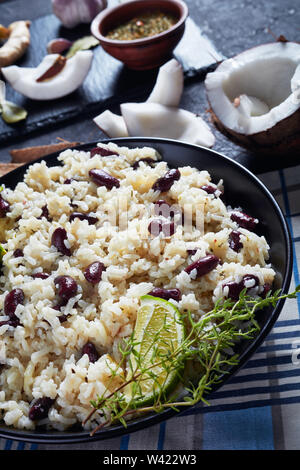 Nahaufnahme der jamaikanischen Reis und rote Bohnen gekocht mit Kokosmilch, gewürzt mit Knoblauch, Zwiebeln und kreolischen Gewürzen in eine Schüssel mit Zutaten im Hinterg Stockfoto