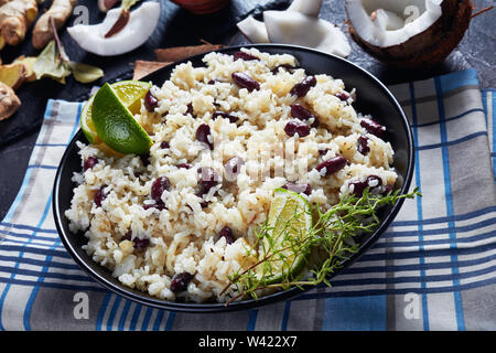 Nahaufnahme der jamaikanischen Reis und rote Bohnen gekocht mit Kokosmilch, gewürzt mit Knoblauch, Zwiebeln und kreolischen Gewürzen in eine Schüssel mit Zutaten im Hinterg Stockfoto