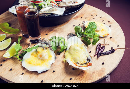 Geöffnete Austern auf Eis Meeresfrüchte frisch und gekocht, serviert mit Sauce auf Holz- fach Stockfoto