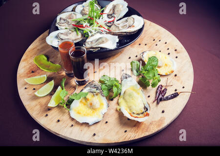 Geöffnete Austern auf Eis Meeresfrüchte frisch und gekocht, serviert mit Sauce auf Holz- fach Stockfoto