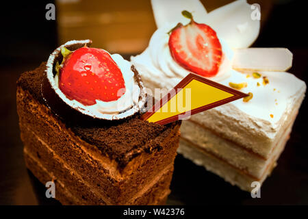 Leckere Stücke Schokolade Kuchen und Butter Kuchen mit Erdbeeren und voller Eis um es mit Obst Nähe zu sehen. Stockfoto