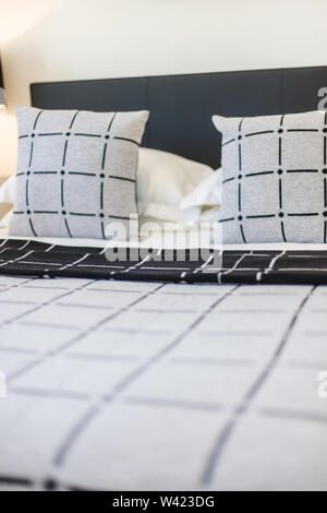 Zwei Kissen mit Design und vier weißen Kissen gehalten auf Kuschelige Betten Stockfoto
