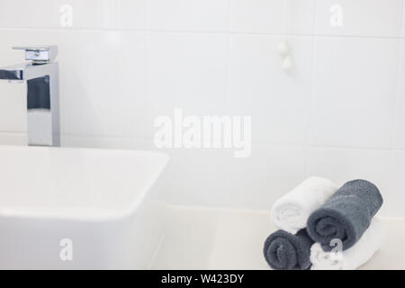 Ansicht eines modernen Waschbecken Design, eine exquisite Wasserhahn und aufgerollten Handtüchern in Schwarz und Weiß Stockfoto