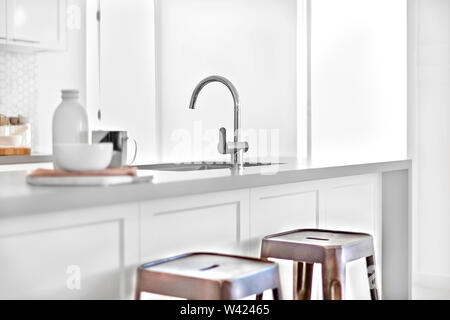 Moderne Küche mit Schwerpunkt der silberne tippen und neben einem Schwarzen und Kunststoff Stühle in der Nähe von einem Eingang, keramische Objekte auf dem Holztisch verwischt. Stockfoto