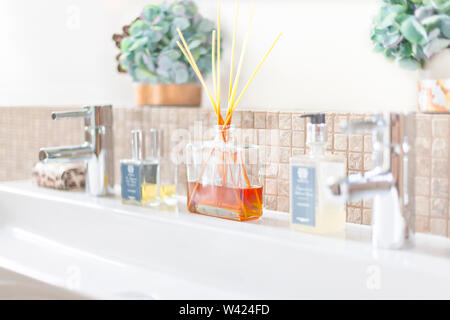 Silber Hahn und weiß Waschtisch mit aromatischen Bambusstäbe, Parfüm Diffusor und Lufterfrischer in Bad neben dekorativen Elemente Stockfoto