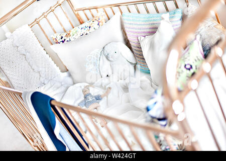 Baby Bett mit Kissen und Kaninchen Teddybären mit dem Spielzeug auf dem seidenen Bettlaken, es gibt einen Zaun mit glänzend aussehen der Bereich der Bettdecke, Kleines Bett Stockfoto