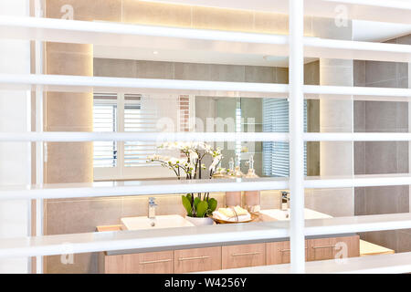 Badezimmer Blick durch das offene Fenster schließen oben mit weißen Holzmöbeln Bars, das Bad Spiegel und Waschbecken und auf der Holzschrank Zähler tippen, weißen f Stockfoto