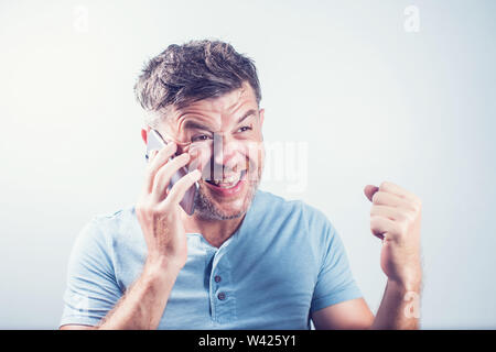 Hübscher junger Mann mit Handy glücklich Stockfoto