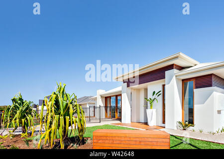 Diese moderne Häuser mit riesigen weißen Wänden einen Garten mit Rasen und Pflanzen, meist sind es weiße Wände und Balken aus Holz Dekoration mit hohen Stockfoto