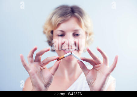 Beendigen Sie zu rauchen. Nahaufnahme des Schönen Happy Weiblich brechen Zigarette. Portrait von Lächelnden Frau mit Zigarette in der Hand gebrochen. Gesunder Lebensstil Con Stockfoto