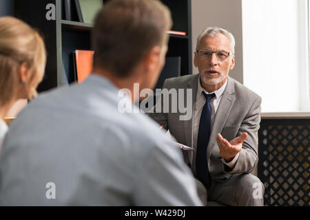 Grauhaarige zuversichtlich Professional gut aussehende Psychotherapeut consulting Ehepaar Stockfoto