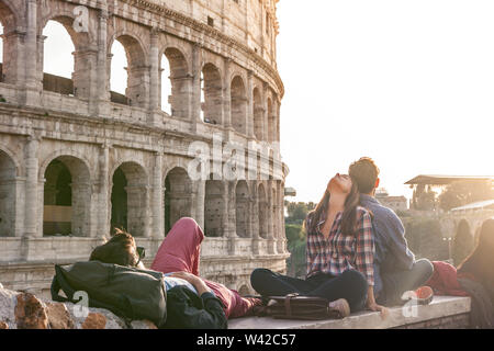 Drei glückliche junge Freunde Sitzen und Liegen vor dem Kolosseum in Rom Stockfoto